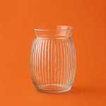 Clear glass vase with ribbed texture on an orange background