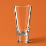 Clear glass shot glass on an orange background