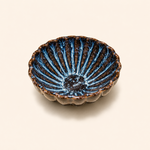 Ceramic bowl with blue and brown glaze on a beige background