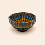 Ceramic bowl with blue interior and brown exterior on a beige background