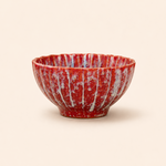 Red ceramic bowl with white speckles on a beige background