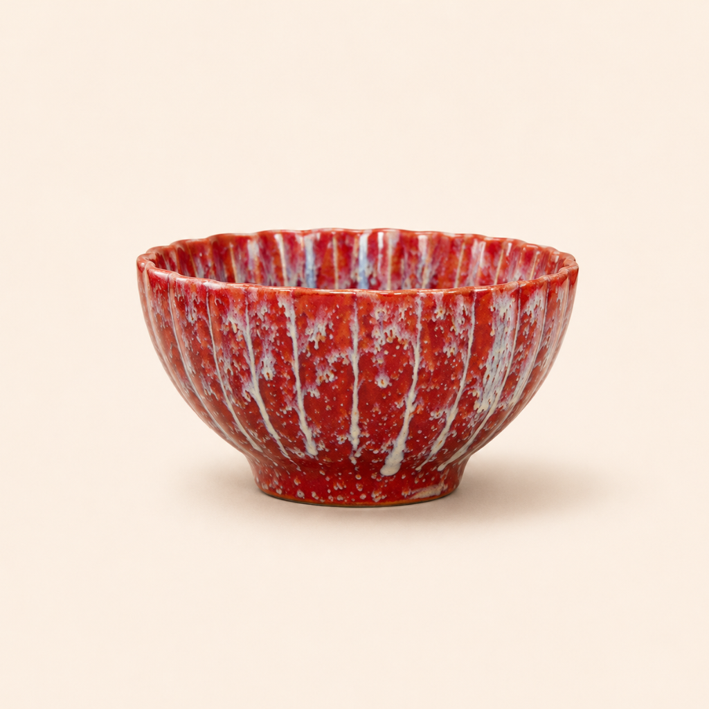 Red ceramic bowl with white speckles on a beige background