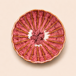 Decorative plate with pink textured center and brown rim on a beige background
