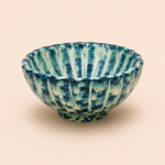Blue and green ceramic bowl on a beige background