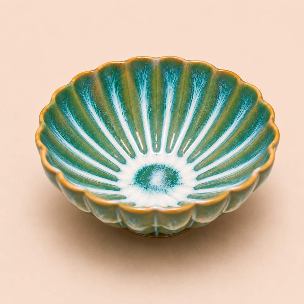 Green ceramic bowl with scalloped edge on a beige background