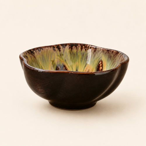 Ceramic bowl with brown and green glaze on a beige background