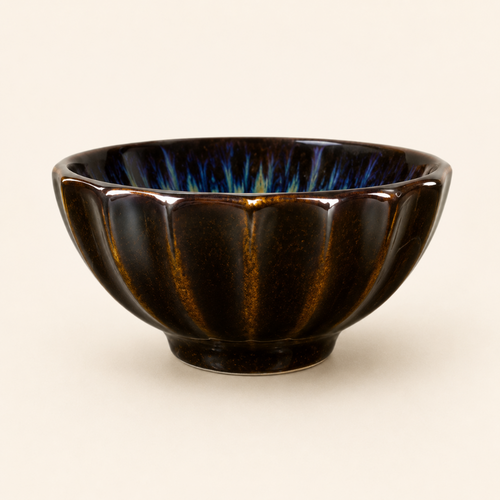 Black ceramic bowl with ribbed texture on a beige background