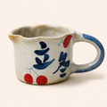 Ceramic cup with blue and red abstract designs on a white background