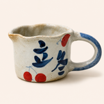 Ceramic cup with blue and red abstract designs on a white background