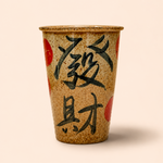 Ceramic cup with black calligraphy and red accents on a beige background