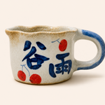 Ceramic cup with blue text and red cherries on a white background