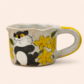 Ceramic mug with a cat and flower design on a beige background