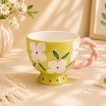 Green mug with floral design on a beige surface