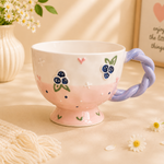 Ceramic mug with floral design and purple handle on a soft background
