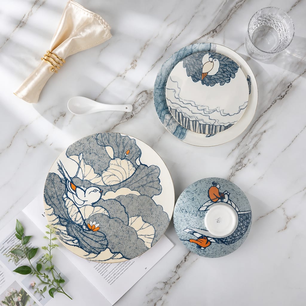 Set of ceramic plates with bird designs on a marble surface