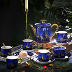 Blue ceramic tea set with gold accents on a dark surface.