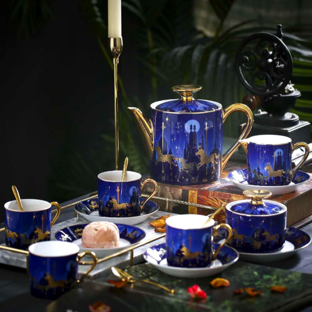 Blue ceramic tea set with gold accents on a dark surface.