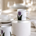 White ceramic cup with purple tulip design on a white pedestal