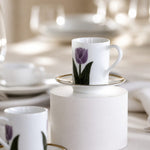 White ceramic cup with purple tulip design on a white pedestal