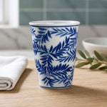 Blue and white ceramic cup with leaf pattern on a wooden surface