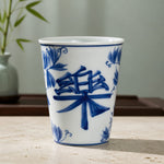 White ceramic cup with blue floral and character design on a wooden surface.