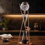 Copper and glass coffee brewing device on a wooden surface with a blurred kitchen background.